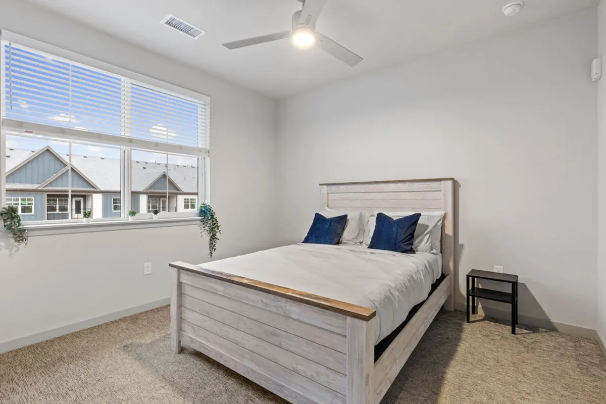 A tranquil bedroom featuring a plush bed with soft linens, a window that allows natural light to fill the room, and a cozy nightstand. The scene exudes a peaceful, restful ambiance ideal for unwinding after a busy day.