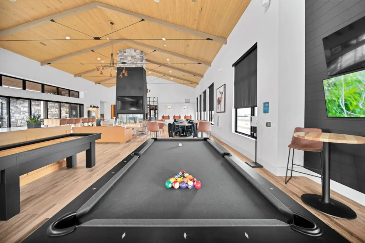 A lively interior scene showcasing a pool table, cozy fireplace, spacious dining area, and large windows letting in ample daylight. This is a hub for residents to relax, play games, or socialize after a long shift.