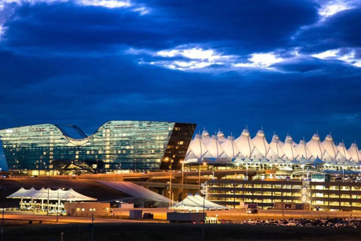 A striking view of modern architecture with illuminated roof structures, reflective glass surfaces, and an adjacent parking structure, conveying the dynamic atmosphere of airport arrivals and departures.
