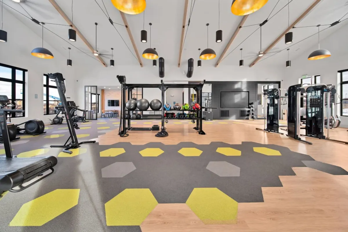 A well-equipped fitness center with weightlifting equipment, exercise mats, colorful weights, and large windows offering abundant natural light, creating an energizing space for workouts.